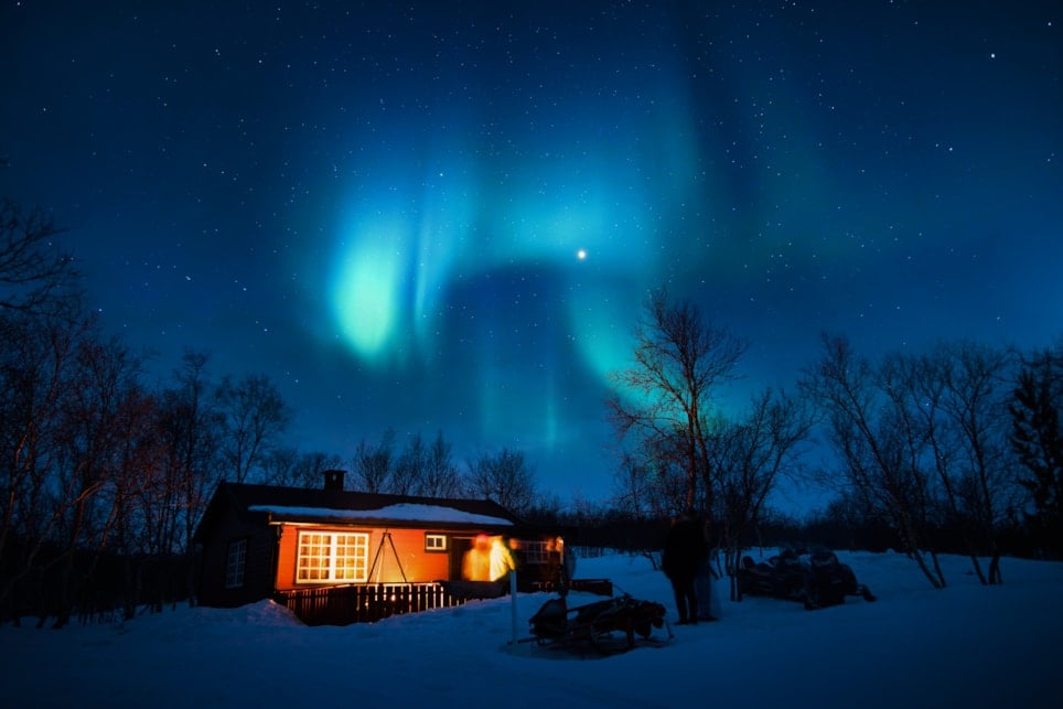 Hytte om natten med nordlys på himmelen